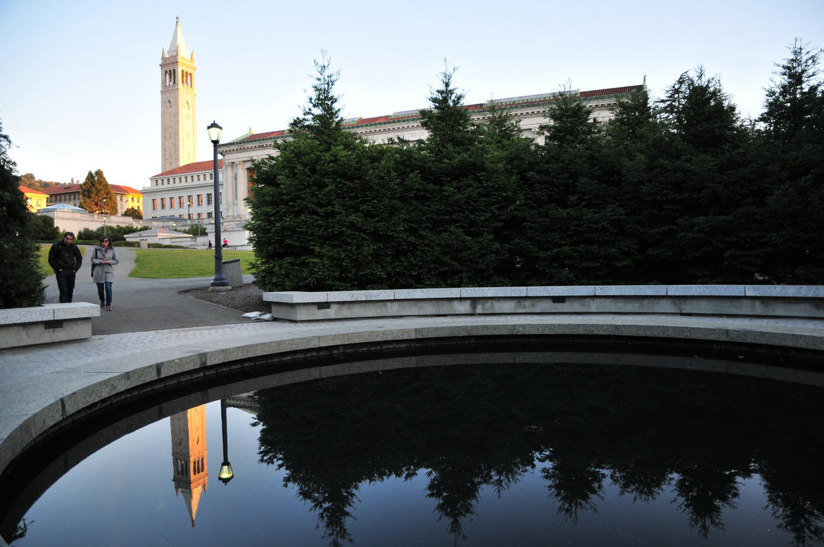 Students walking through campus by fountain with Campanile in background